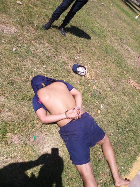 Uno de los detenidos por transportar drogas en un muñeco de peluche yace en el suelo de un espacio verde de La Plata mientras personal de la policía lo custodia