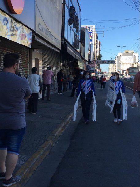 Locales vacíos y personal de la municipalidad repartiendo sillas plásticas