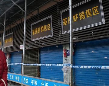 Mercado de Mariscos de Wuhan cerrado con faja y con una persona que circula con barbijo