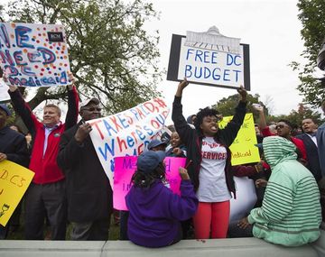 Decenas de personas muestran pancartas durante una concentración para solicitar al Senado el desbloqueo del debate sobre el presupuesto de Washington D. C.