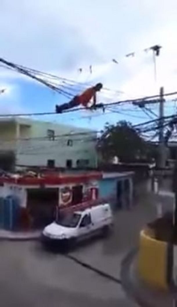 Un hombre hace ejercicio colgado de los cables de electricidad