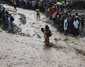 Personas intentan cruzar el río La Digue, en Haití, debido al derrumbe del único puente que conecta con el sur, tras el paso del huracán Matthew.