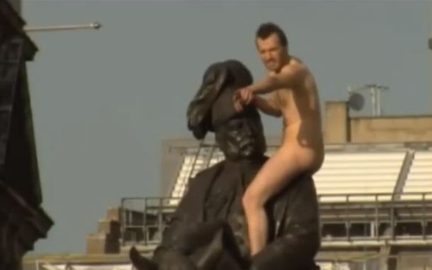 Un hombre desnudo sobre la estatua del duque de Cambridge