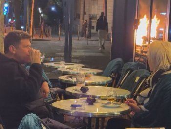 Una pareja de parisinos distendidos en un bar en medio del fuego y los disturbios que sacuden Francia Una pareja de parisinos distendidos en un bar en medio del fuego y los disturbios que sacuden Francia