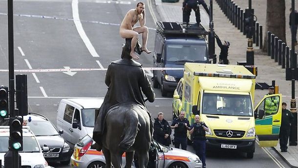 Un hombre desnudo trepa a una gran estatua de Londres