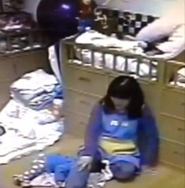 Una niñera inmoviliza a un bebe con sus piernas para hacerlo dormir