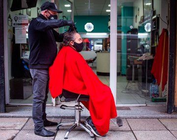 Un peluquero sacó el sillón a la vereda para atender a sus clientes