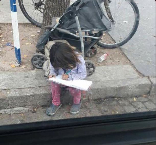 La nena haciendo los deberes mientras pide limosna