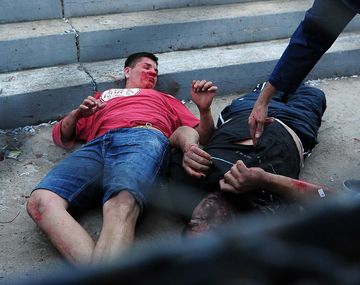 Mario Becerra, de remera roja, yace herido en el piso