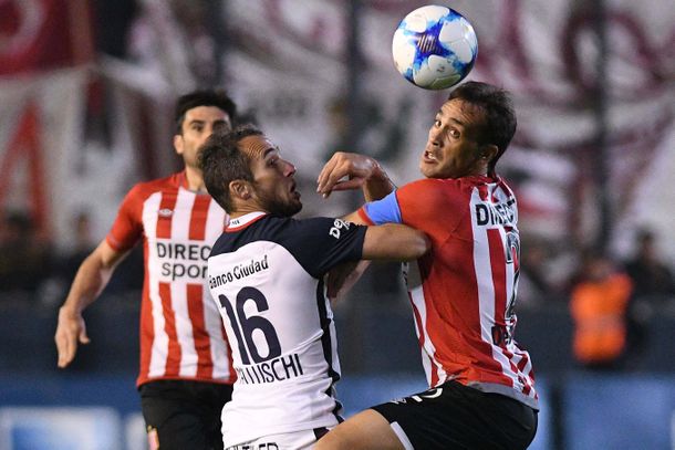 Bellluschi y Desábato pelean por la pelota ante la mirada del Chapu Braña