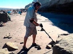 Con un detector de metales, un hombre busca tesoros en una playa