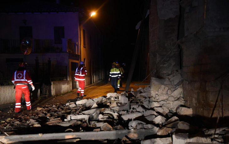 Un grupo de bomberos y rescatistas camina por los escombros