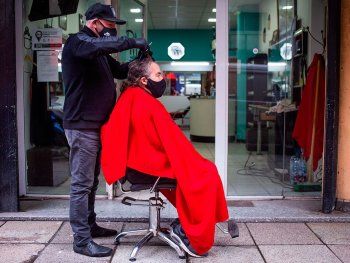 Un peluquero sacó el sillón a la vereda para atender a sus clientes
