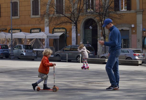 Un padre juega con sus hijas en una plaza