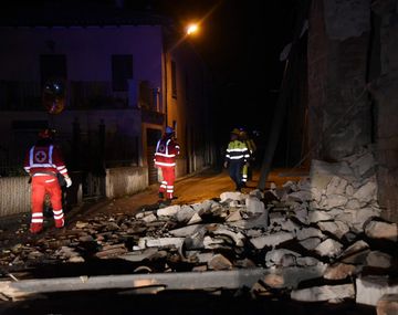 Un grupo de bomberos y rescatistas camina por los escombros