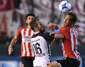 Bellluschi y Desábato pelean por la pelota ante la mirada del Chapu Braña