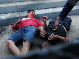 Mario Becerra, de remera roja, yace herido en el piso Mario Becerra, de remera roja, yace herido en el piso