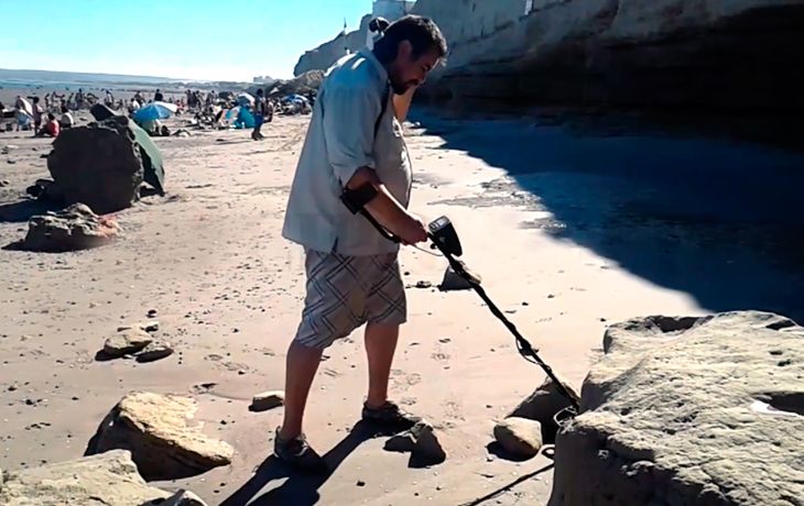 Con un detector de metales, un hombre busca tesoros en una playa