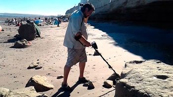 Con un detector de metales, un hombre busca tesoros en una playa Con un detector de metales, un hombre busca tesoros en una playa