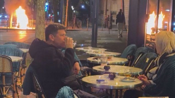 Una pareja de parisinos distendidos en un bar en medio del fuego y los disturbios que sacuden Francia