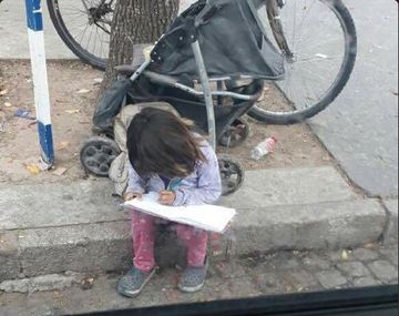 La nena haciendo los deberes mientras pide limosna