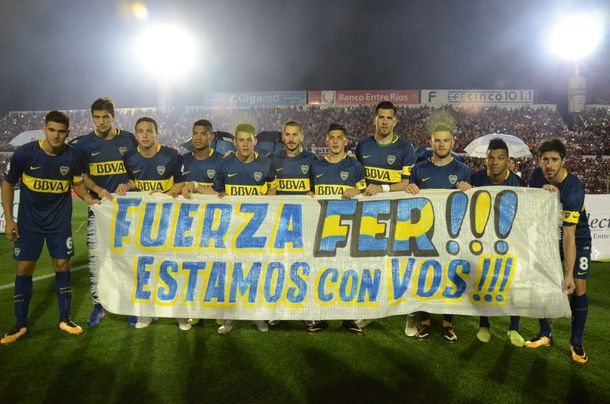 El plantel xeneize con la bandera dedicada a Fernando Gago