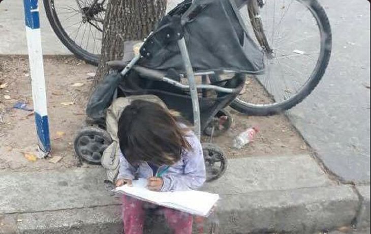 La nena haciendo los deberes mientras pide limosna