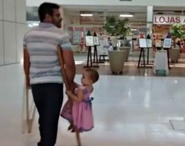 Un padre carga a su pequeña hija en su muleta