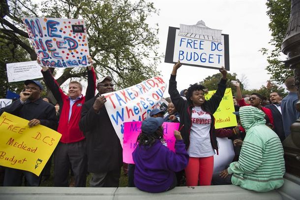 Decenas de personas muestran pancartas durante una concentración para solicitar al Senado el desbloqueo del debate sobre el presupuesto de Washington D. C.