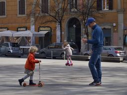 Un padre juega con sus hijas en una plaza, en Trastevere, ante la suspensi&oacute;n del ciclo escolar en todo Italia